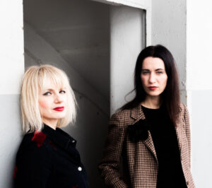 Catharina Rüß and Sui Kemmer (Garlands) standing in front of an open door leading towards a basement