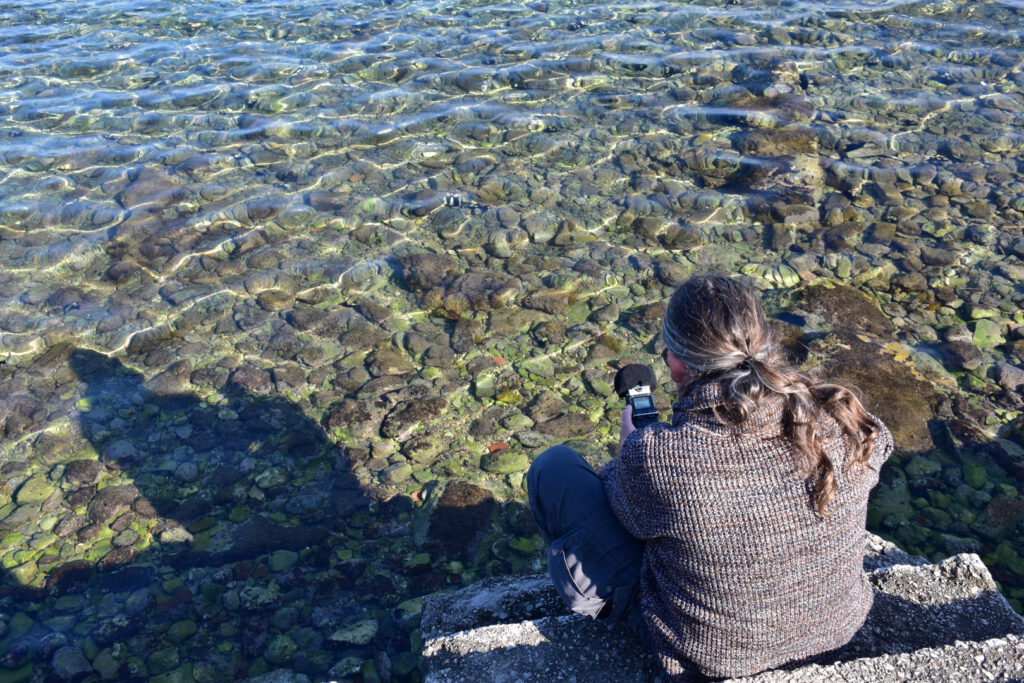 Balthazar Klimt sitting on staris at a pond and holding a recording device